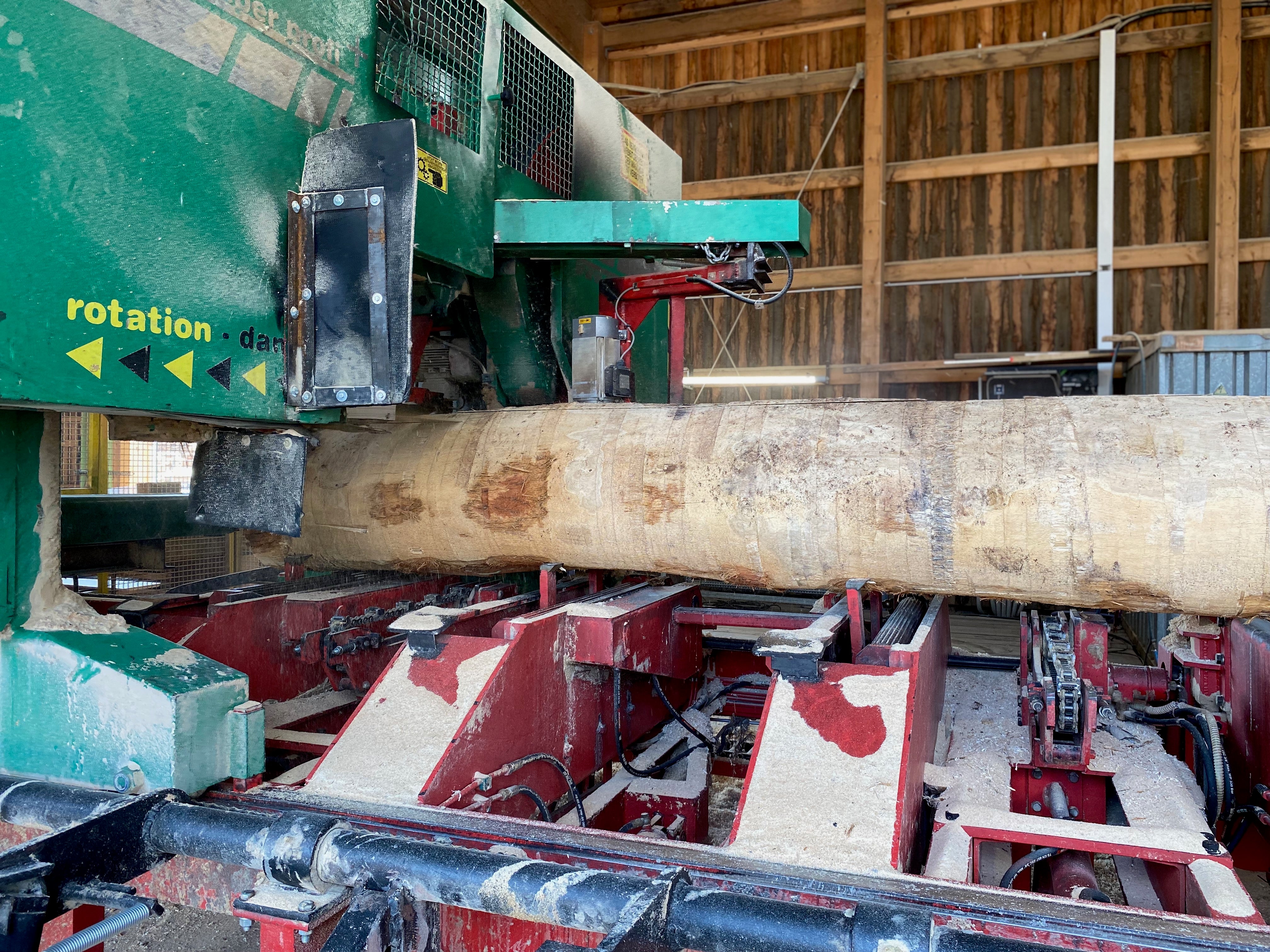 Ein dickerer Baumstamm wird mit der Bandsäge zerschnitten