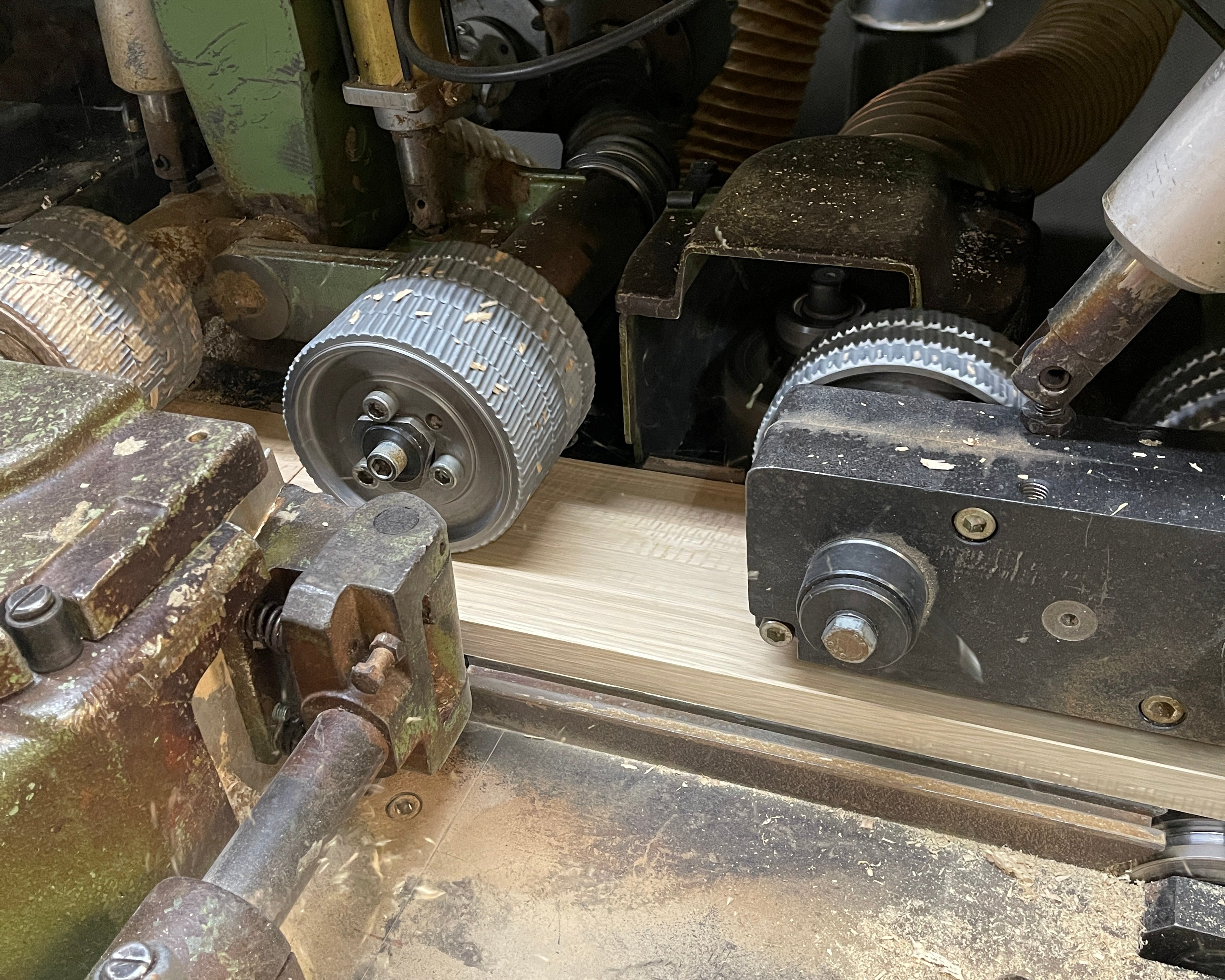 Die Maschine hobelt die Oberfläche des Parkettstücks. Seitlich wird eine Nut gefräst.