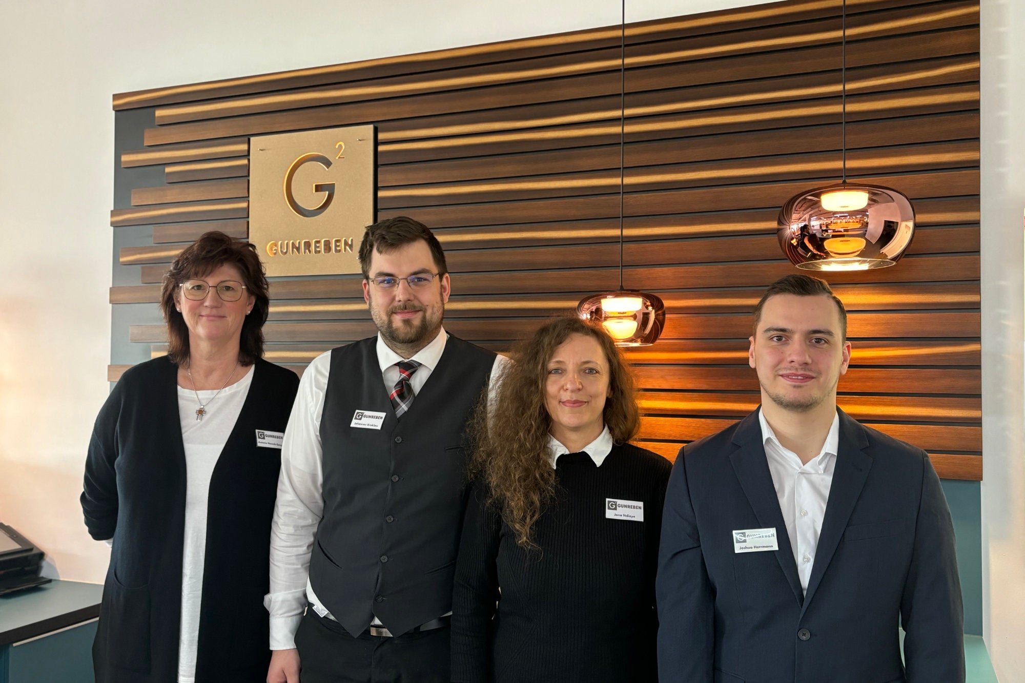 Die Mitarbeiter des Gunreben Showrooms stehen nebeneinander vor dem Gunreben-Logo hinter der Theke.